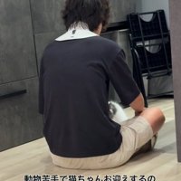 男性の後ろ姿と膝の間にいる猫