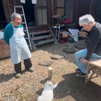 日向ぼっこする猫を囲む老夫婦