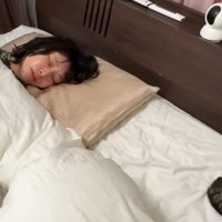 ベッドで寝ている人と2匹の猫