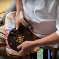 おもちゃの電池を入れ替える人とその様子を見つめる猫