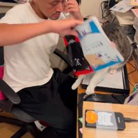 座っている猫の下からノートを取る男性