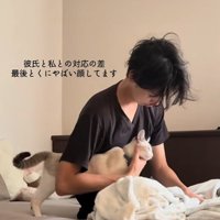 飼い主の腕の隙間に入ってアゴを撫でられている猫