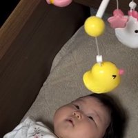 ベッドの上に吊されたおもちゃを見つめる赤ちゃん