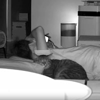 猫と寝転がっている飼い主