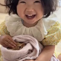 子猫を抱っこしながら笑っている子供（目線ズレ）