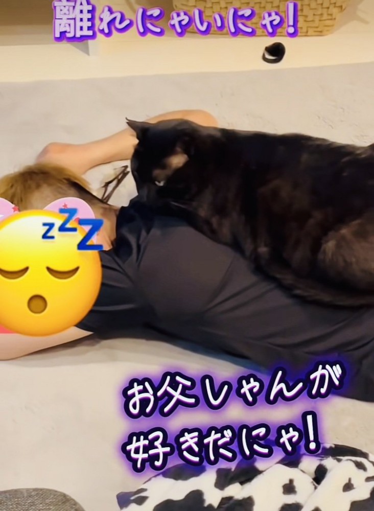 お父さんの背中に乗る黒猫