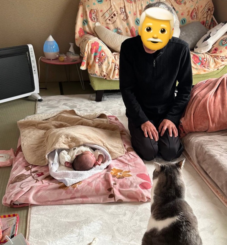 赤ちゃんを見守るじいじと猫