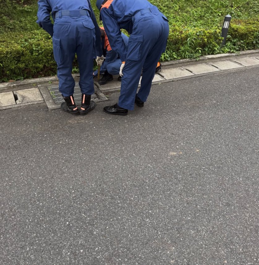 側溝を覗き込む三人の消防士