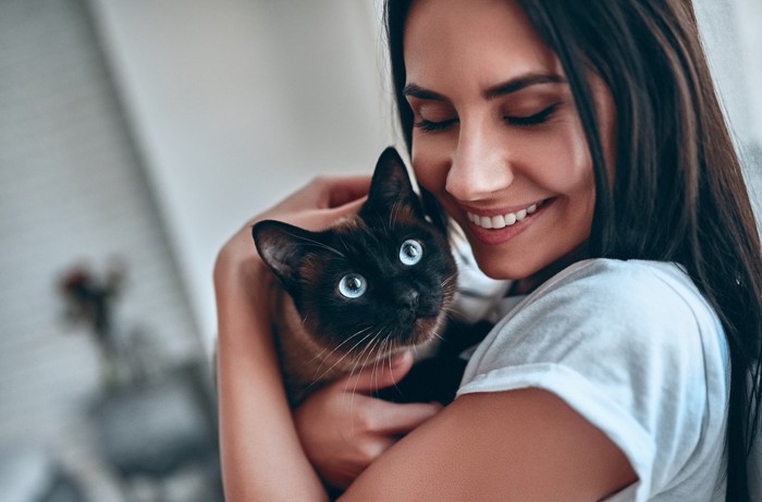 女性に抱っこされている猫