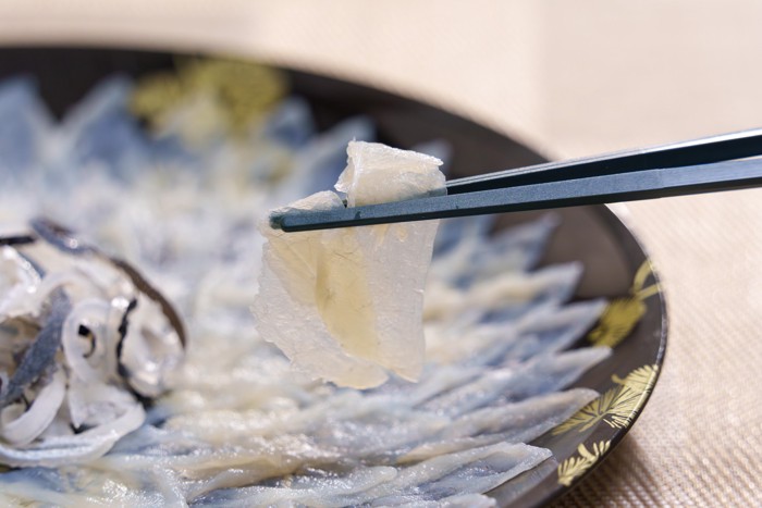 フグの刺身をお箸で持ち上げている様子