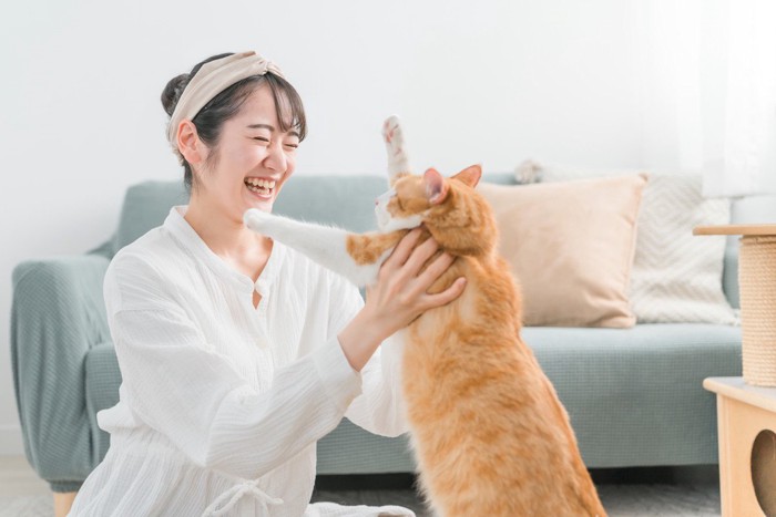猫を抱っこしようとしている笑顔の女性