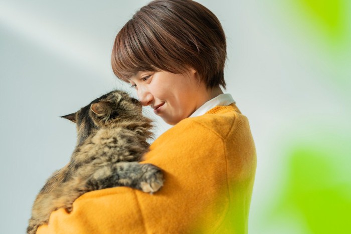 猫を抱いて顔と顔を合わせる女性