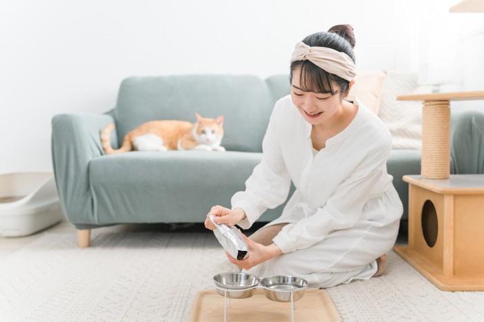 キャットフードを継ぎ足す女性