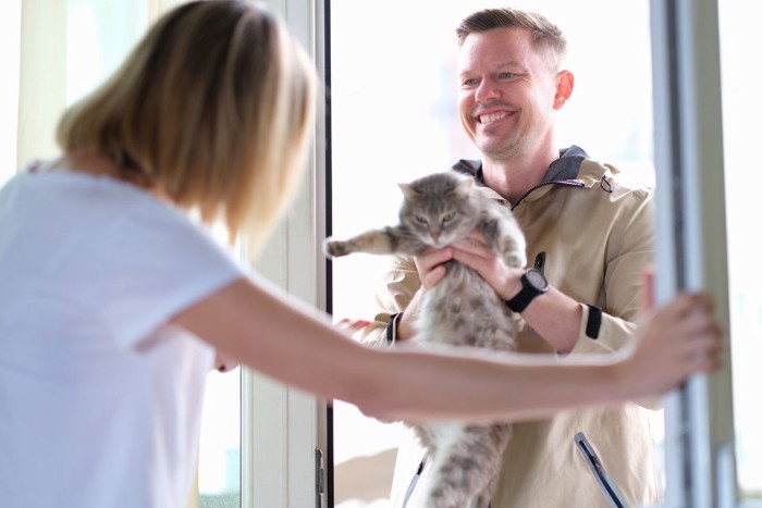 男性に抱かれて目をそらす猫