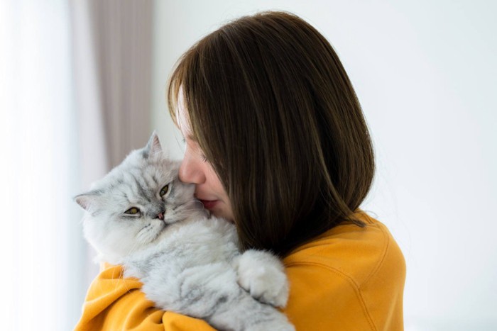 女性に抱きしめられる猫