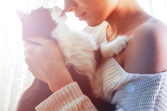 飼い主の女性の花を舐める猫