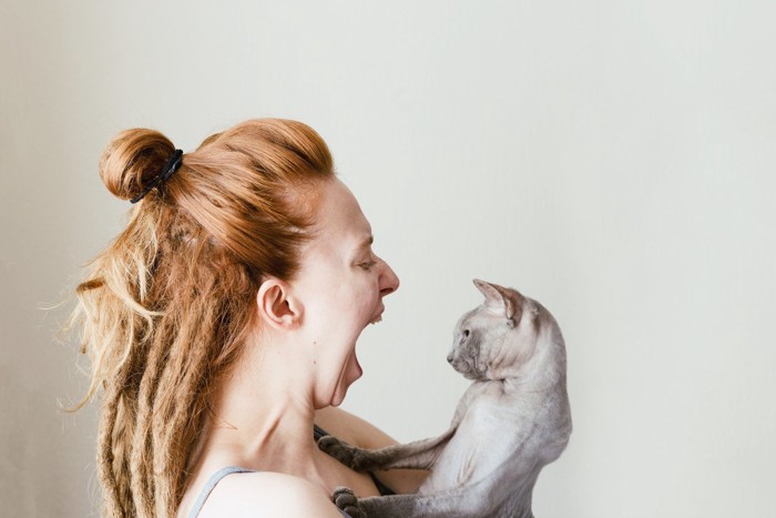 大きな口を開けている女性と猫