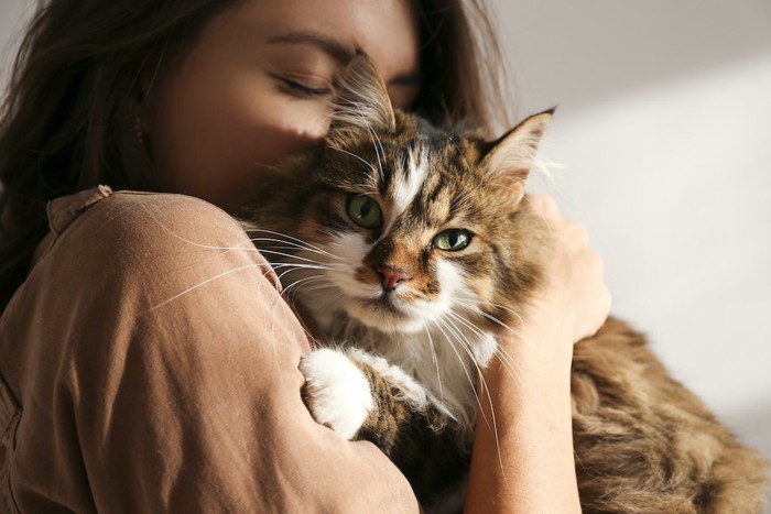 猫を抱っこして目を閉じている女性