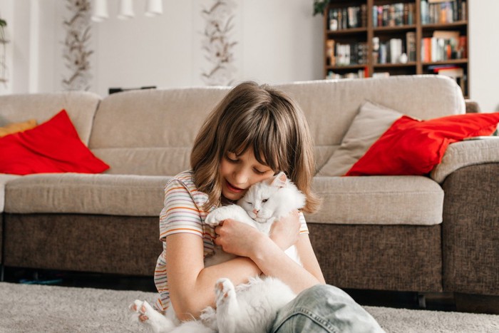 子供に抱きしめられる猫