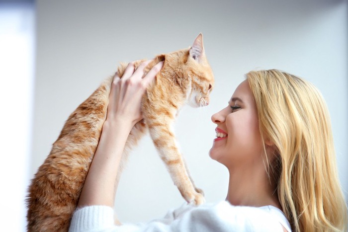 猫を持ち上げる金髪の女性