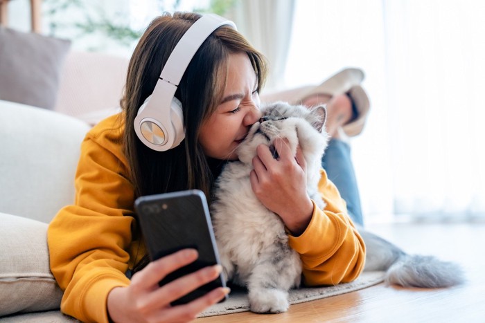 猫をスマホで撮影する女性