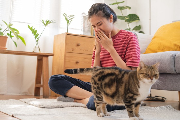 鼻を押さえる女性と猫