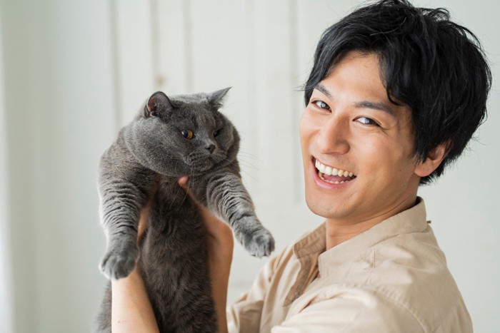 笑顔の男性に持ち上げられている猫