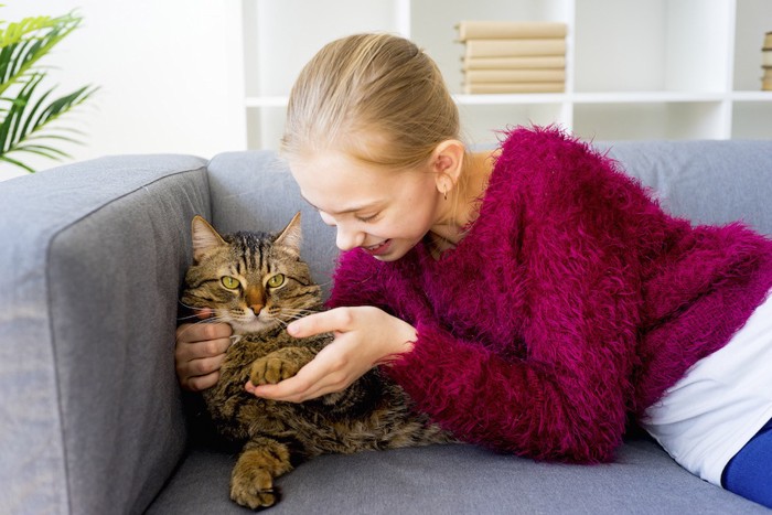 ソファーでくつろぐ女性と猫