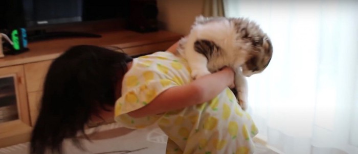 子どもにおんぶされる猫
