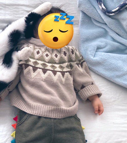 頭に猫の足を乗せられながら熟睡する赤ちゃん