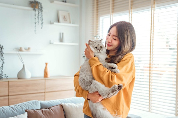 黄色の服の女性に抱っこされる猫