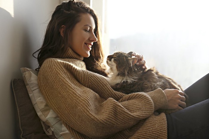 猫を胸の上に乗せて笑顔で撫でる女性