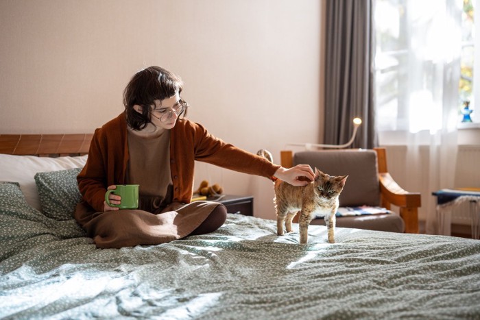 座ってコーヒーを飲む女性と子猫