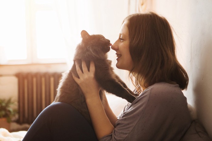 猫に鼻の頭をなめられる女性