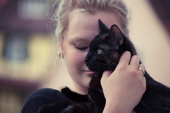 黒猫を抱く若い女性