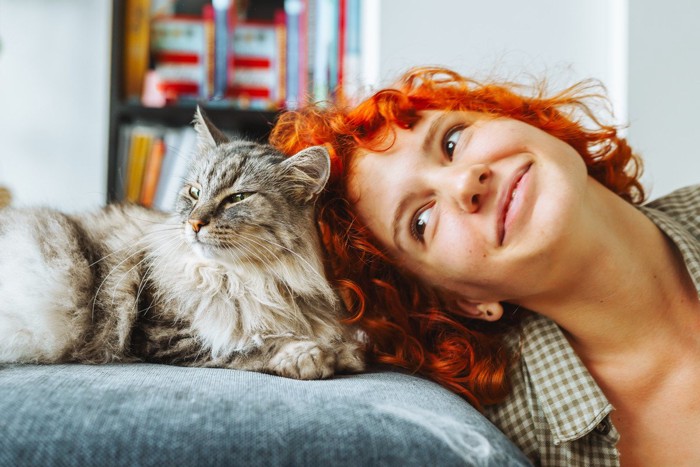頭をくっつけている猫と女性