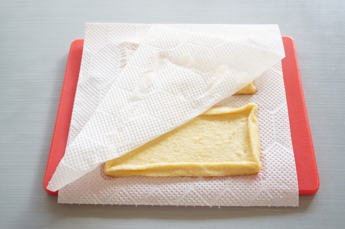 キッチンペーパーで油揚げの油をふき取っている光景