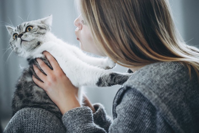 顔を近づける女性を避けようとする猫