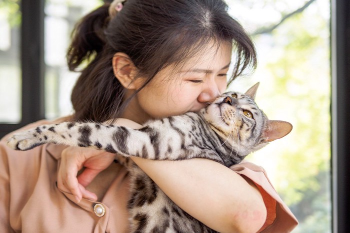 女性に顔をくっつけられてのけ反る猫