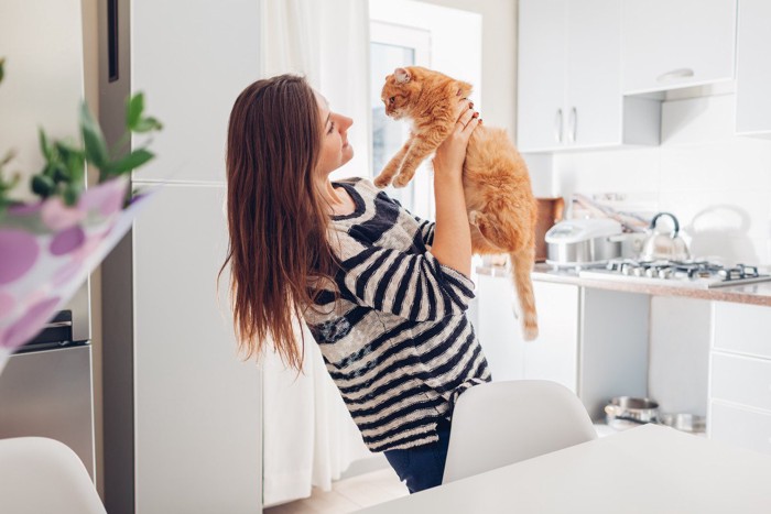 猫を抱き上げる女性