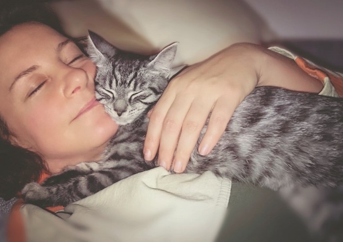 子猫を抱きしめて一緒に眠る女性