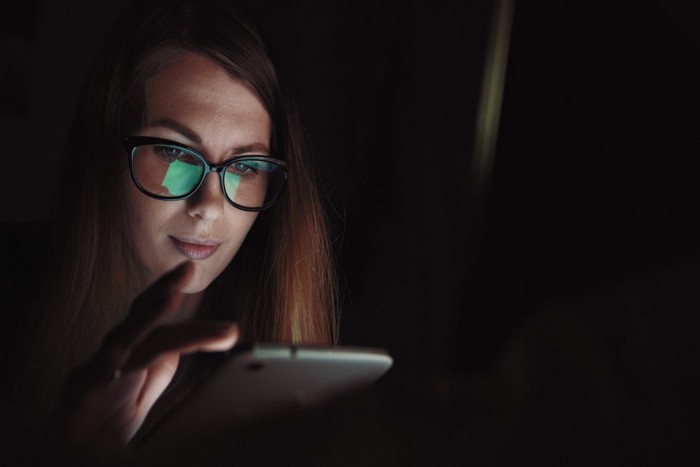 夜更けにスマホの画面を見つめる女性