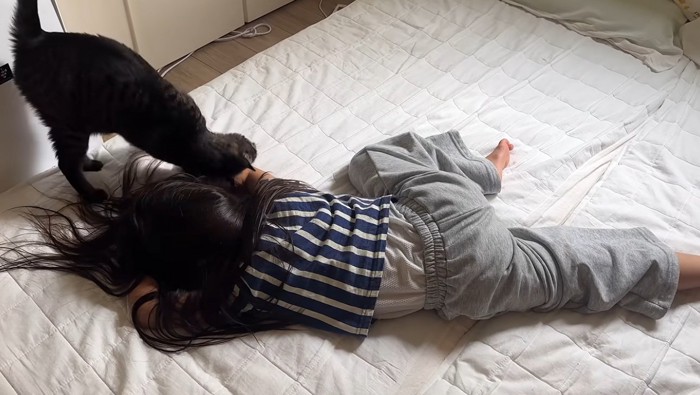 倒れる真似をしている女の子と猫
