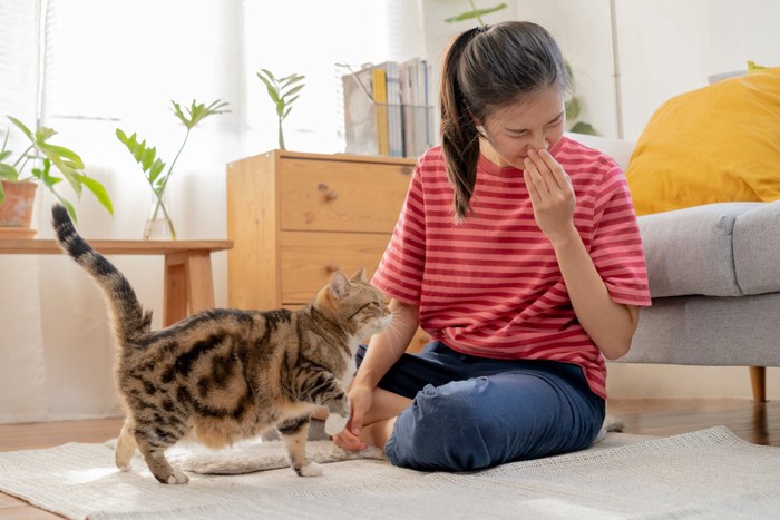 鼻をつまむ女性と猫