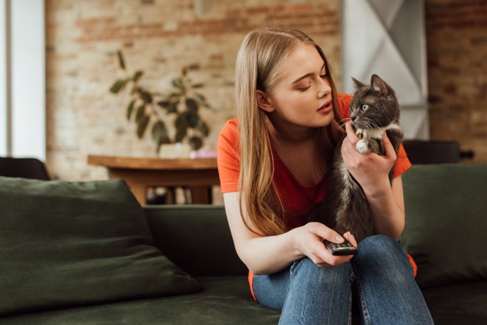 猫を抱きかかえて目を合わせようとする女性