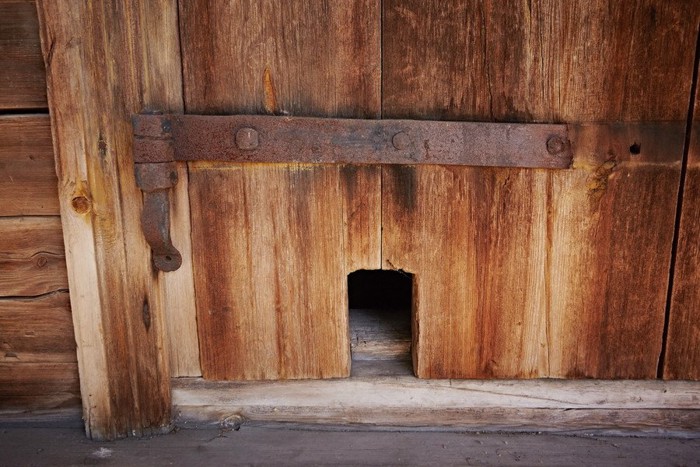 古い木製ドアに作られた猫用の出入り口