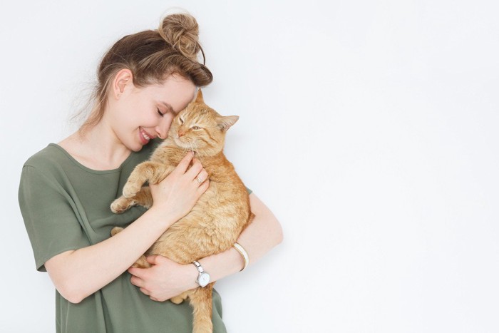 緑のシャツの女性に抱っこされる猫