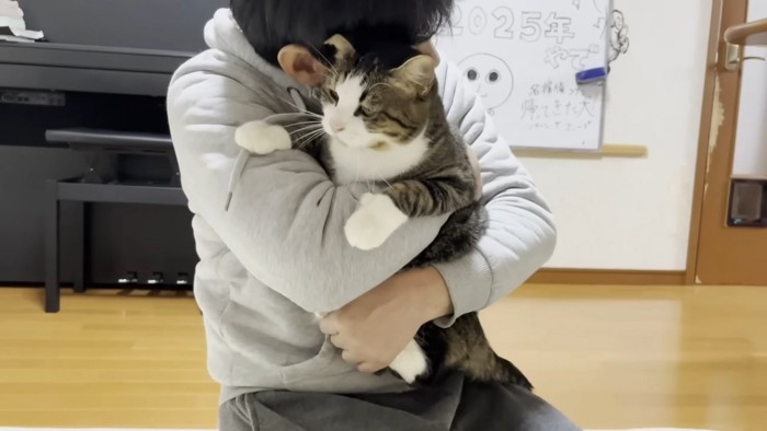 男性が猫を抱きしめている様子