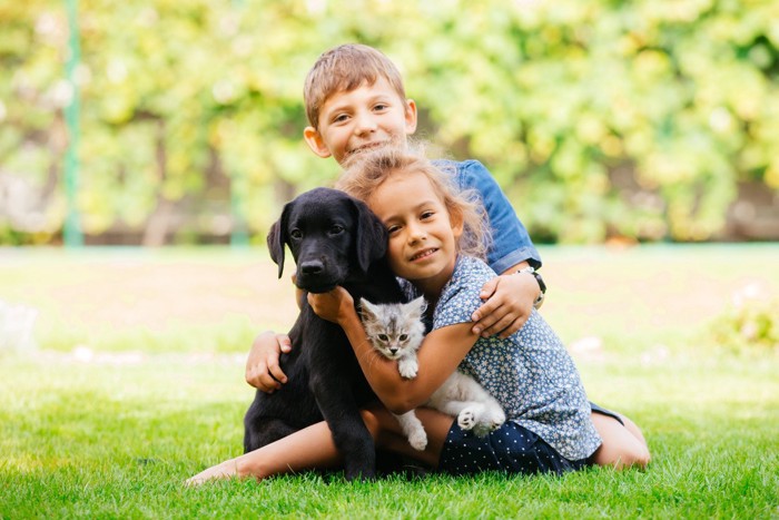 子供たちに抱かれる犬と猫