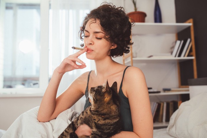 猫を抱いてタバコを吸う女性